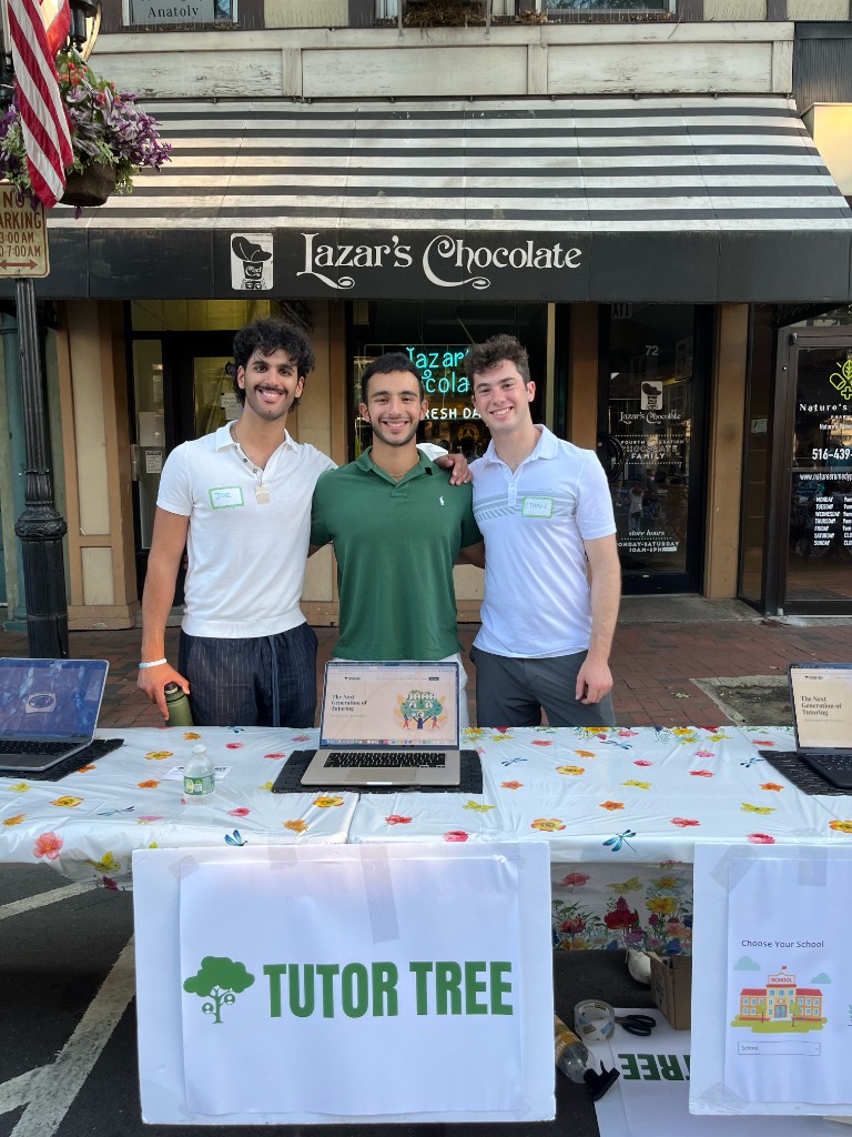 Tutor Tree team at a community table with laptops and signage